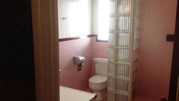 Un baño con inodoro, secamanos y cabina de ducha de vidrio.
