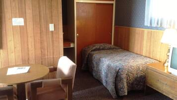 A small room with a bed, a chair, a table, and a TV.