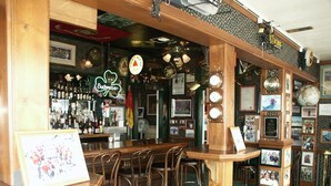 A bar with wooden furniture, a neon sign, and various framed pictures on the walls. - Bridgeport Inn (Bridgeport)