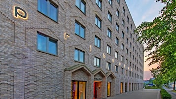 Ein modernes Hotel mit Backsteinfassade, zahlreichen Fenstern und einem gut beleuchteten Eingang.