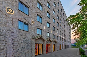 Ein modernes Hotel mit Backsteinfassade, zahlreichen Fenstern und einem gut beleuchteten Eingang.
