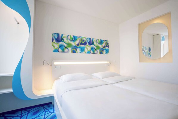 Una habitación de hotel moderna con una cama, una obra de arte abstracto en la pared, una mesita de noche y un espejo.