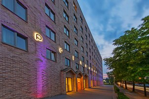 Ein mehrstöckiges Hotel mit Ziegelaußenwand, beleuchteter Beschilderung und blauem Himmel.