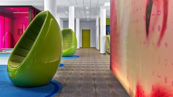 Un intérieur moderne avec des sièges aux formes arrondies évoquant des haricots verts, un sol à motifs et un mur orné de motifs abstraits.