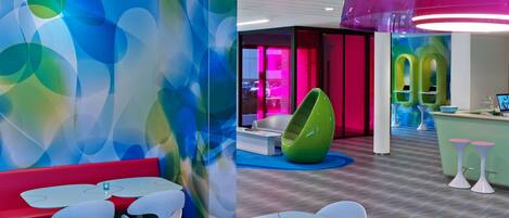 A modern interior with colorful abstract wall art, a vibrant hanging lamp, and a green egg-shaped chair.
