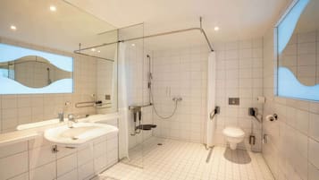 Ein modernes Badezimmer mit großem Spiegel, Waschbecken, Toilette und Duschbereich.