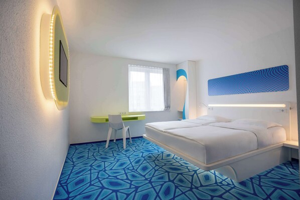 Una habitación de hotel moderna con una cama, un escritorio y una silla.
