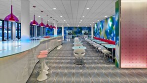 Een modern restaurant met een lange toonbank, barstoelen en tafels met stoelen.