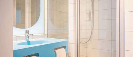 A bathroom with a blue sink, a mirror, and a glass shower enclosure.