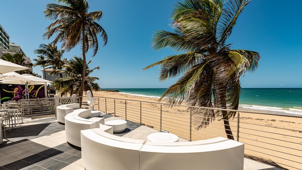 A beachside lounge with white seating and a view of the ocean.