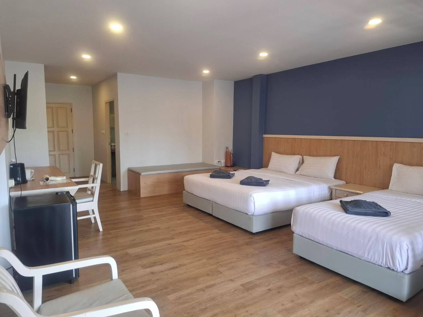 A hotel room with two beds, a desk, a chair, and a TV.
