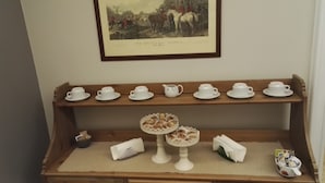 A display of tea cups, saucers, and a teapot on a wooden shelf. - Guest House Calamatta (Rome)