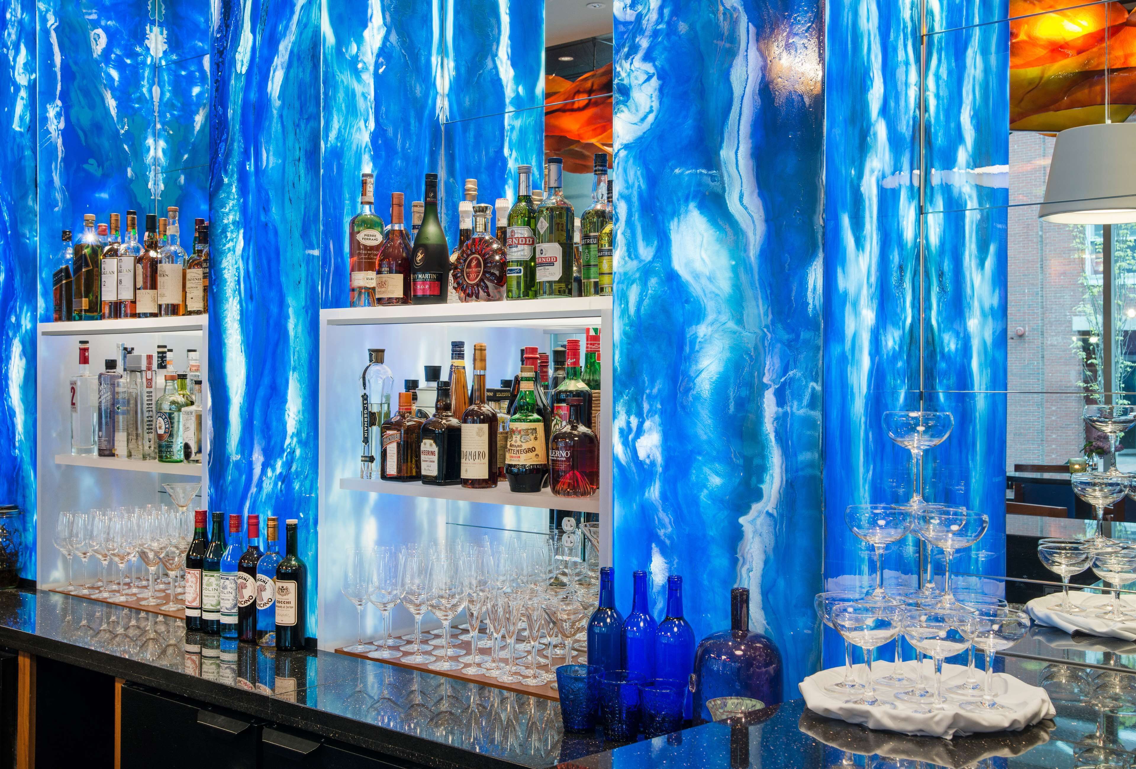 Una zona de bar con estantes llenos de botellas de licores y vasos.