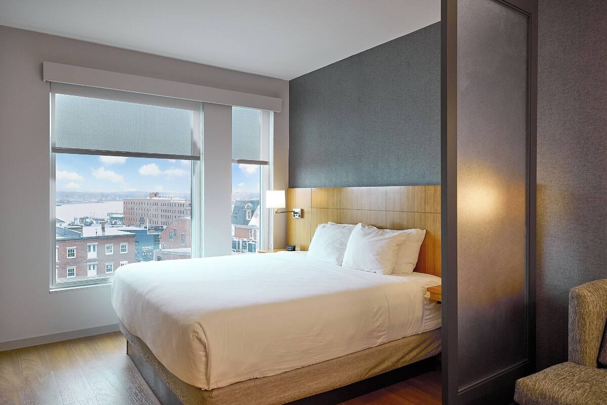 A hotel room with a large bed, a view of the city, and a modern design.
