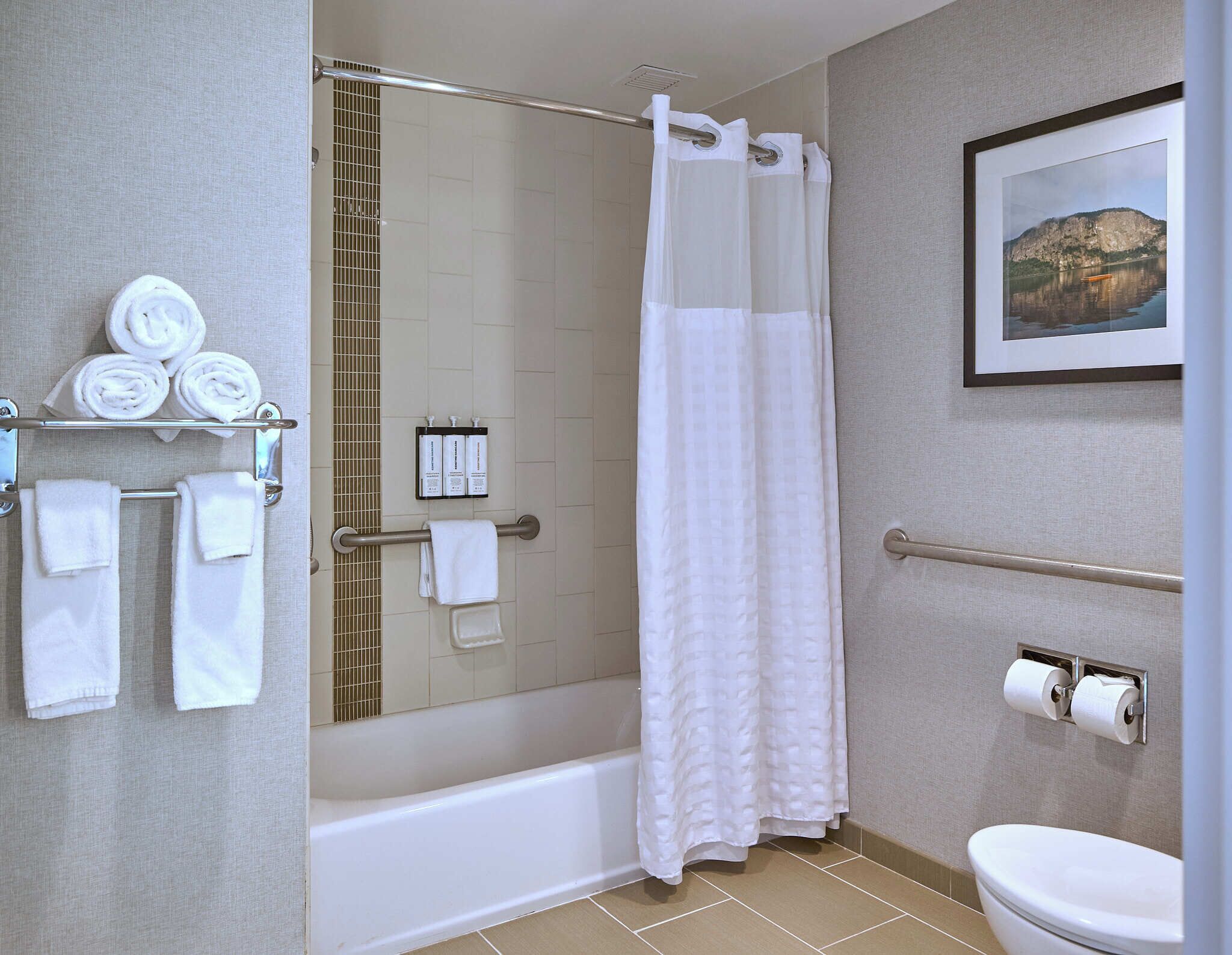 A bathroom with a bathtub, toilet, shower curtain, and towels.