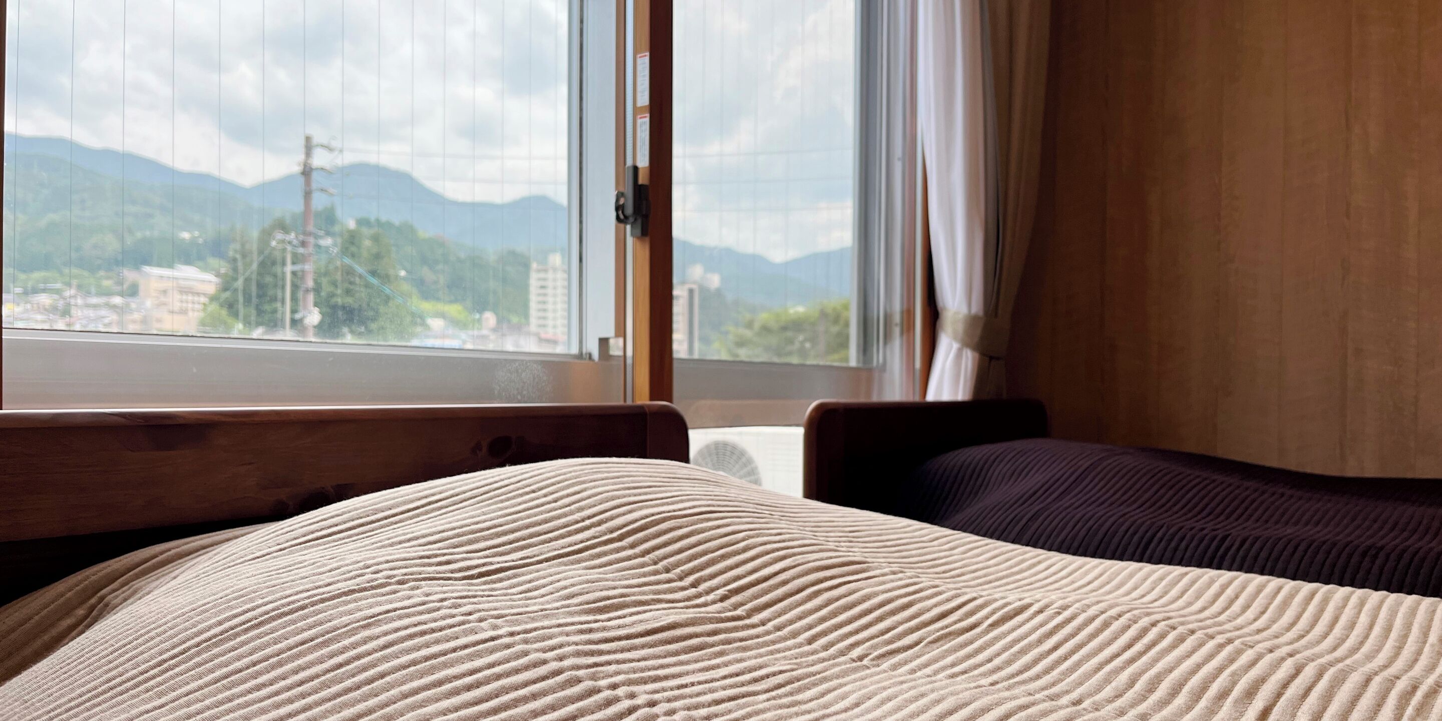 Habitación de hotel con cama, ventana y vista a las montañas, además de cabecero de madera.