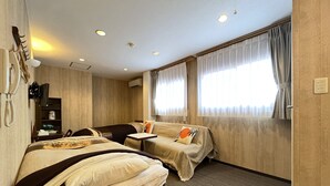 Quarto de hotel com duas camas, uma escrivaninha, uma cadeira, telefone e televisão.