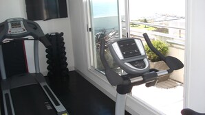 A gym with treadmills and exercise equipment, a large window with a view of the outdoors. - Mercure Montevideo Punta Carretas (Montevideo)