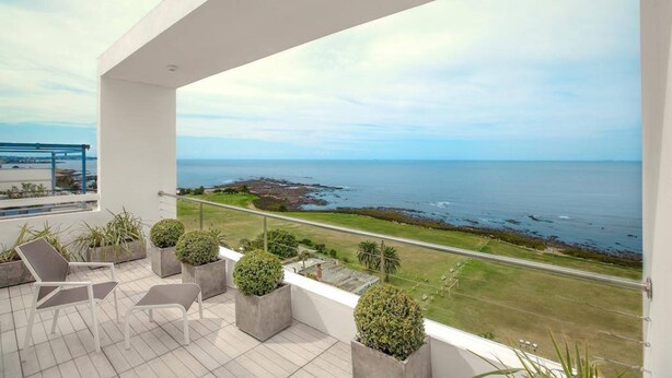 A balcony with a view of the sea, potted plants, and outdoor furniture. - Mercure Montevideo Punta Carretas (Montevideo)