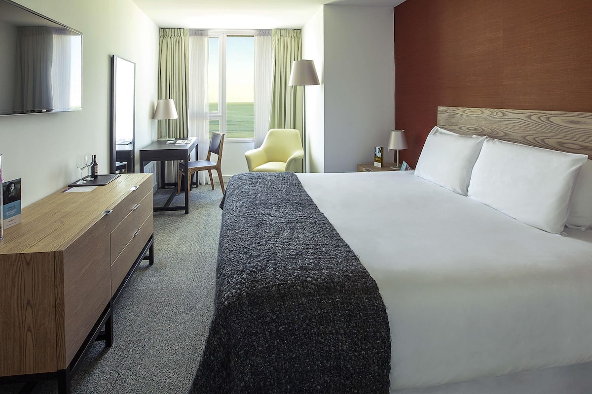 Une chambre d’hôtel équipée d’un lit, d’un bureau, d’une chaise et offrant une vue sur l’extérieur.