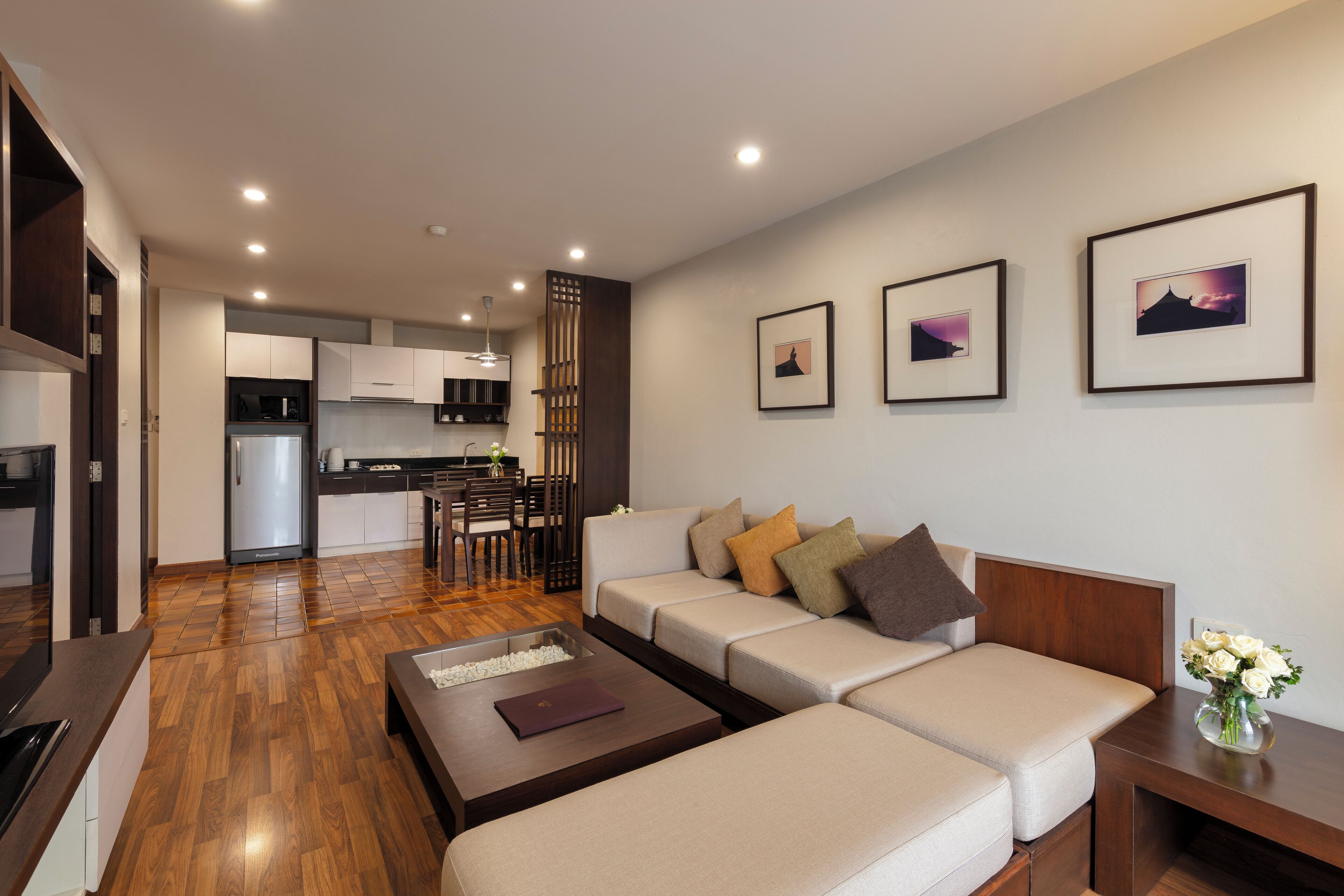 A modern living room with a sofa, coffee table, and a dining area with chairs and a table.