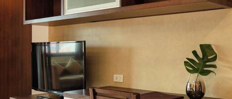 Una sala moderna con televisor de pantalla plana, muebles de madera y una planta.
