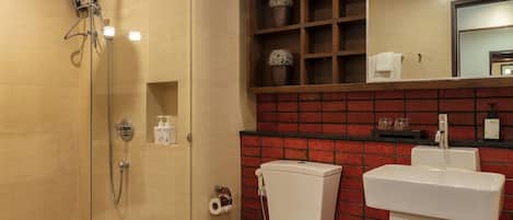 Een badkamer met een douchecabine van glas, een wit toilet en een wastafel.