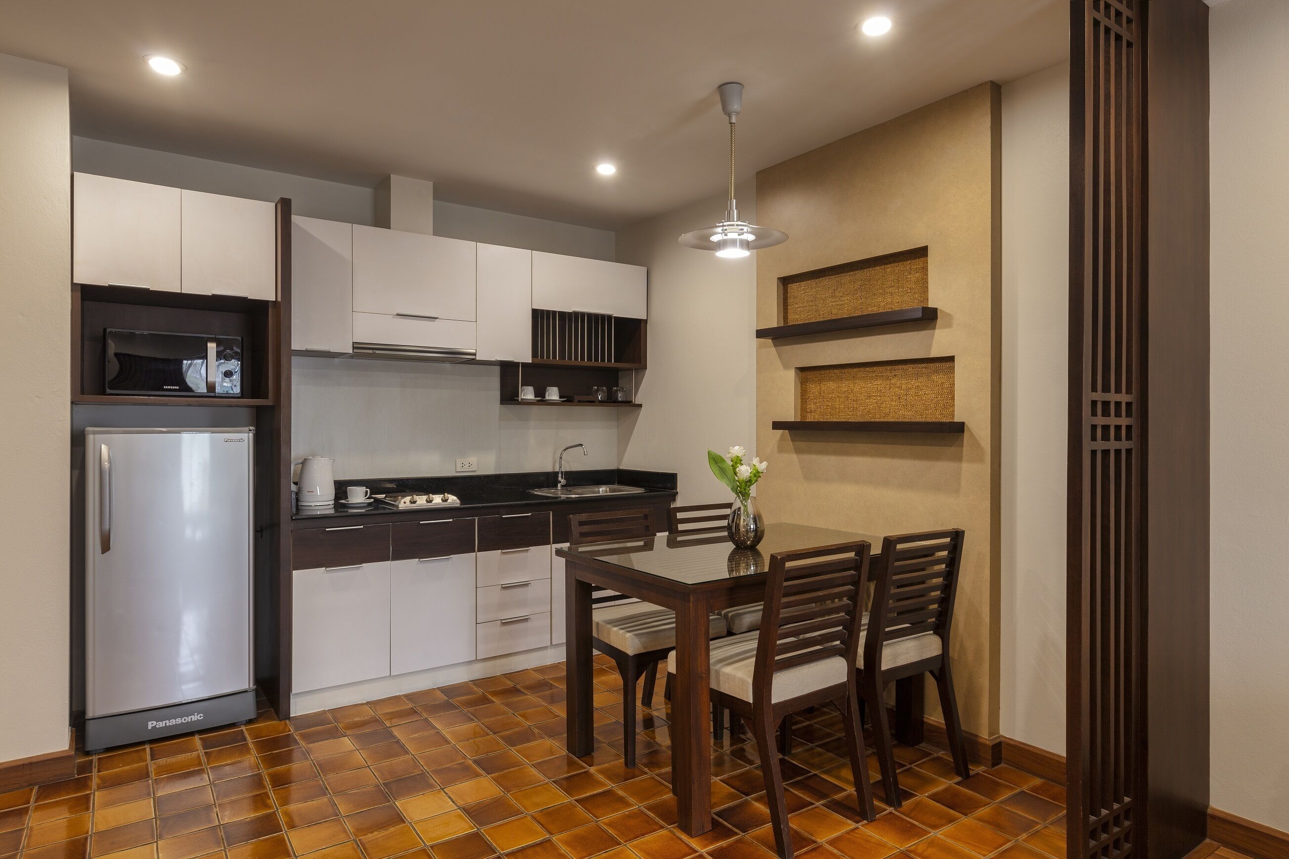 A compact kitchen with a refrigerator, stove, and dining table with chairs.