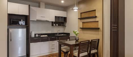Una cocina compacta con refrigerador, estufa y mesa de comedor con sillas.