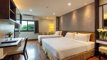A hotel room with two beds, a desk, and a chair.