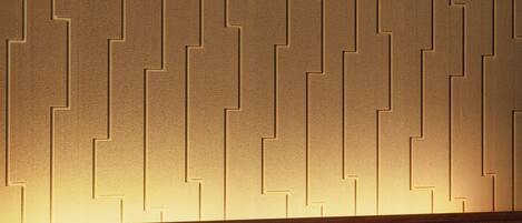 Un interior moderno con una pared de diseño geométrico, una encimera de madera y una lámpara colgante negra.