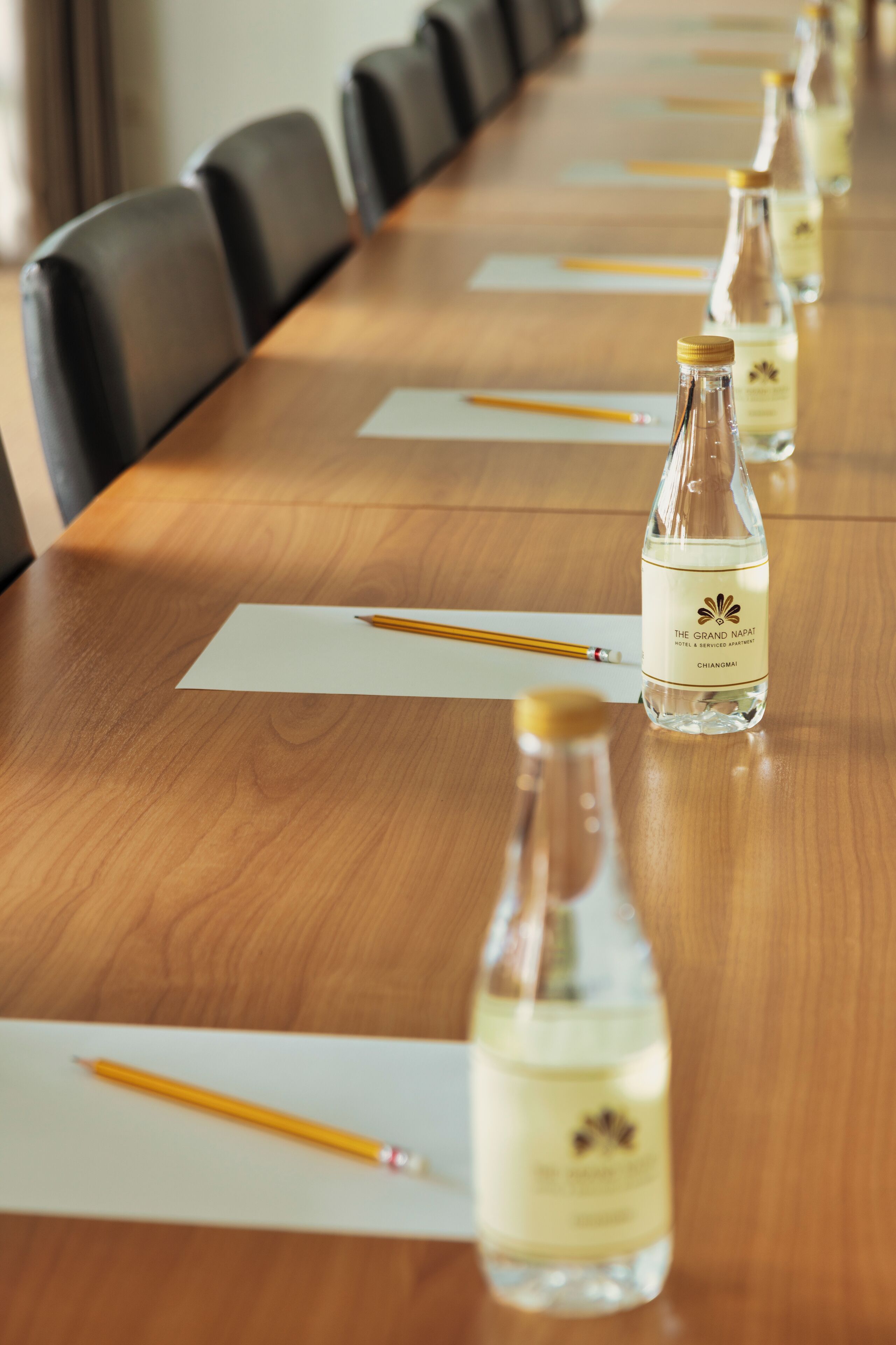 Una mesa de conferencias con botellas de The Grand Napat, un lápiz y documentos.