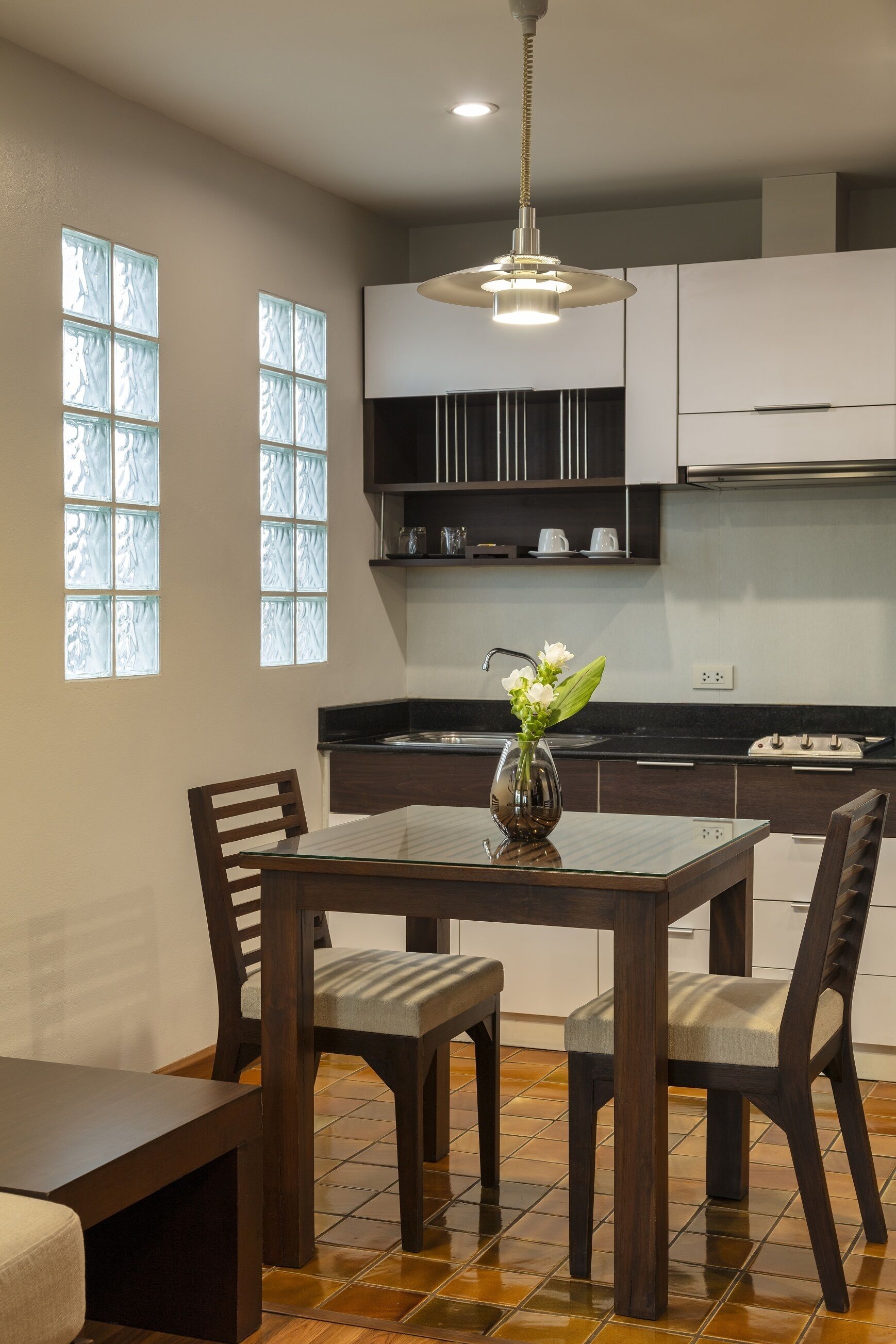 A modern kitchen with dark cabinetry, a central island, and a vase with flowers.