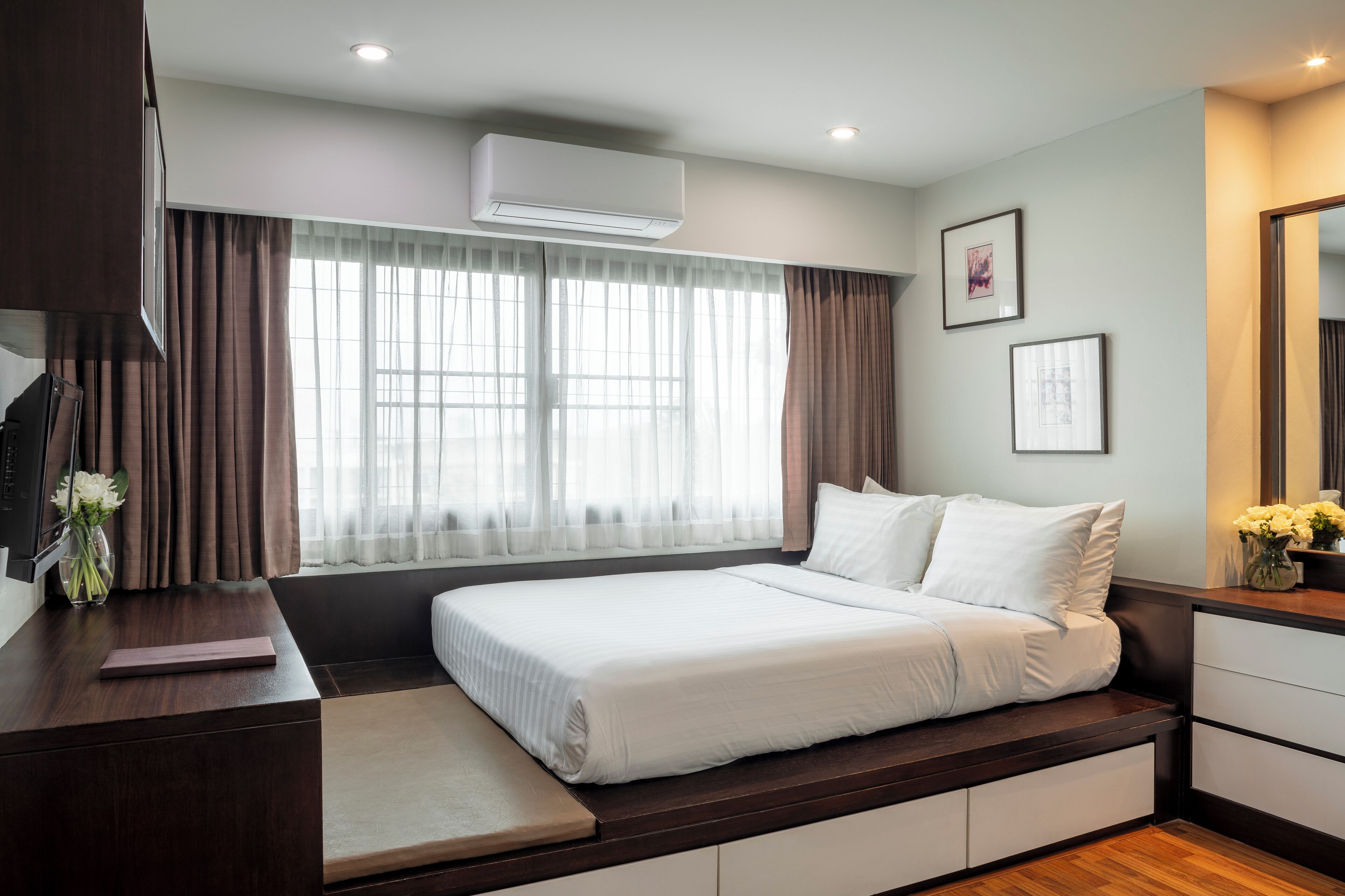 A modern hotel room with a large bed, a desk, and a window with curtains.