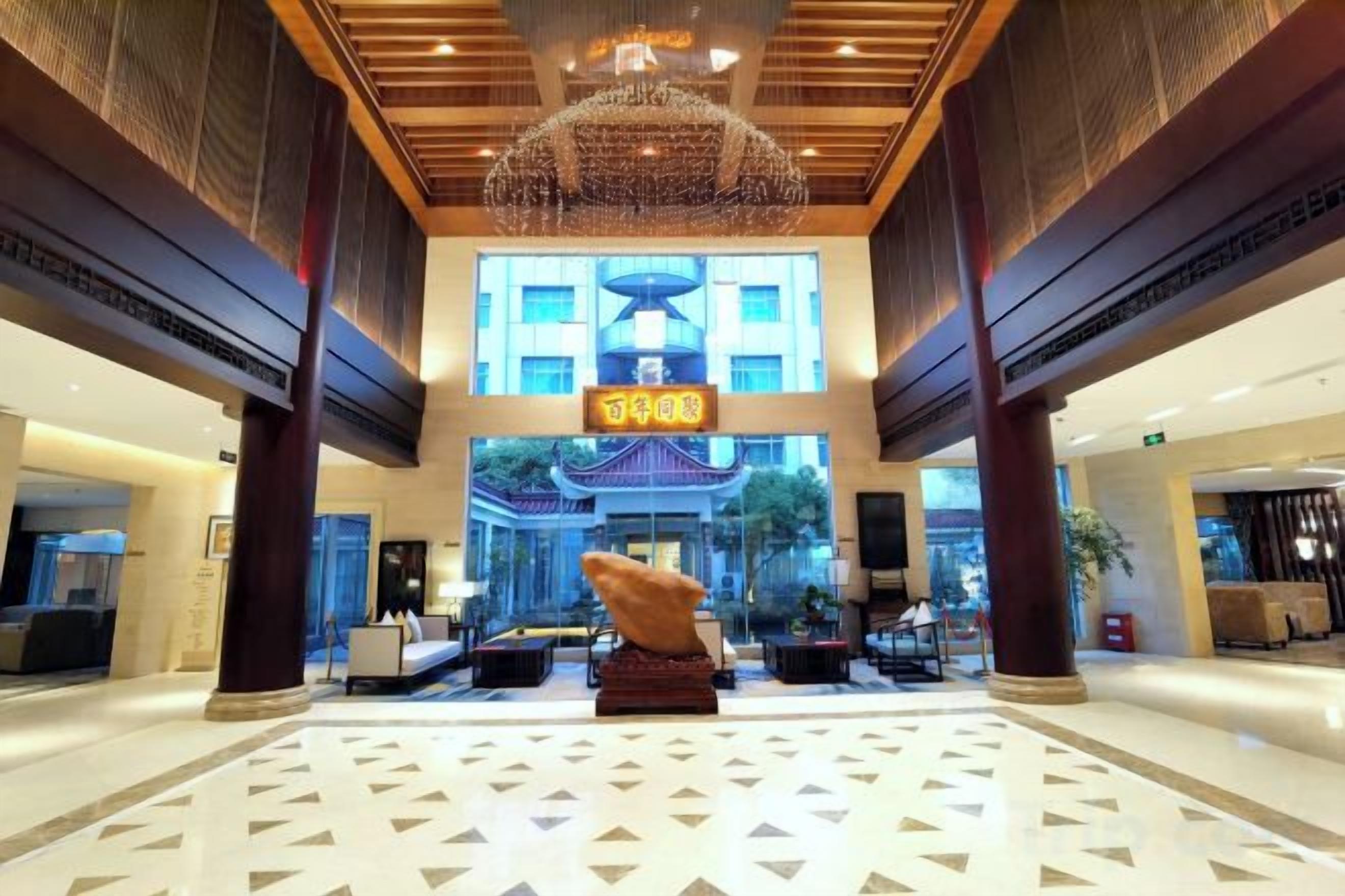 A hotel lobby with a large chandelier, a reception desk, and a traditional Asian-style entrance.