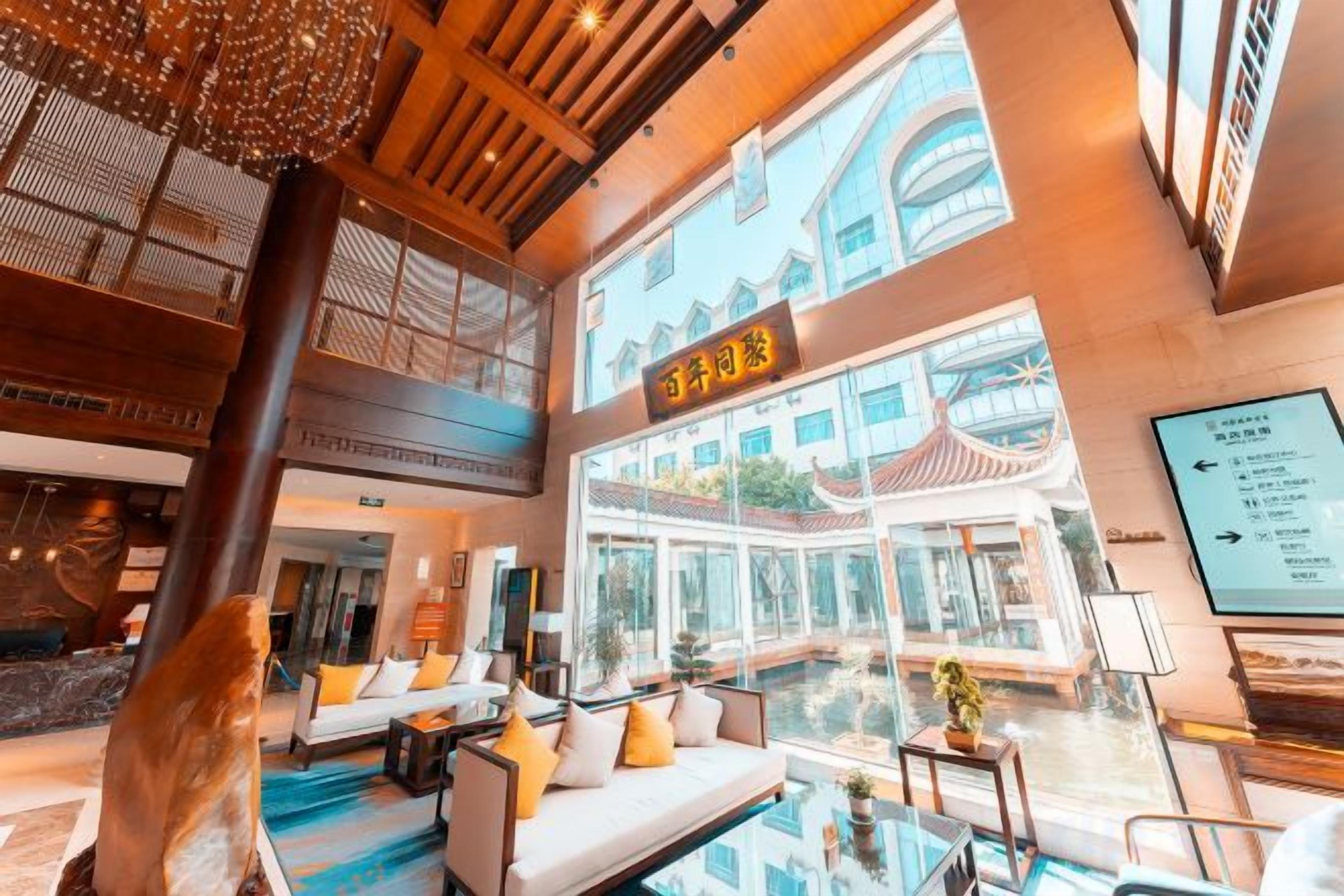 A hotel lobby with a large open space, a reception desk, and a seating area with a pool view.
