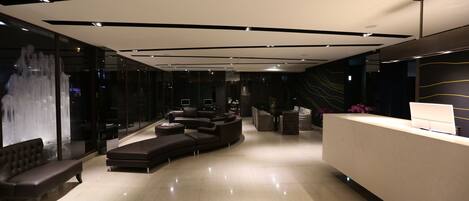 A modern lobby with a reception desk, seating area, and a large window with a view of the outside.