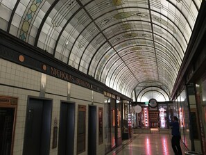 A subway station with a curved glass ceiling, tiled walls, and a sign for 'Nicholas Building'.
