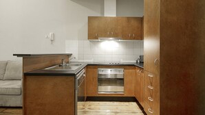 Una cocina compacta con armarios de madera, horno empotrado y encimera.