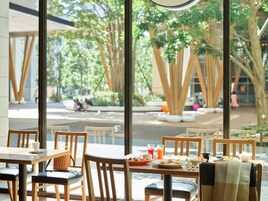 Un comedor con mesas y sillas de madera, y vistas a la calle y a los árboles.
