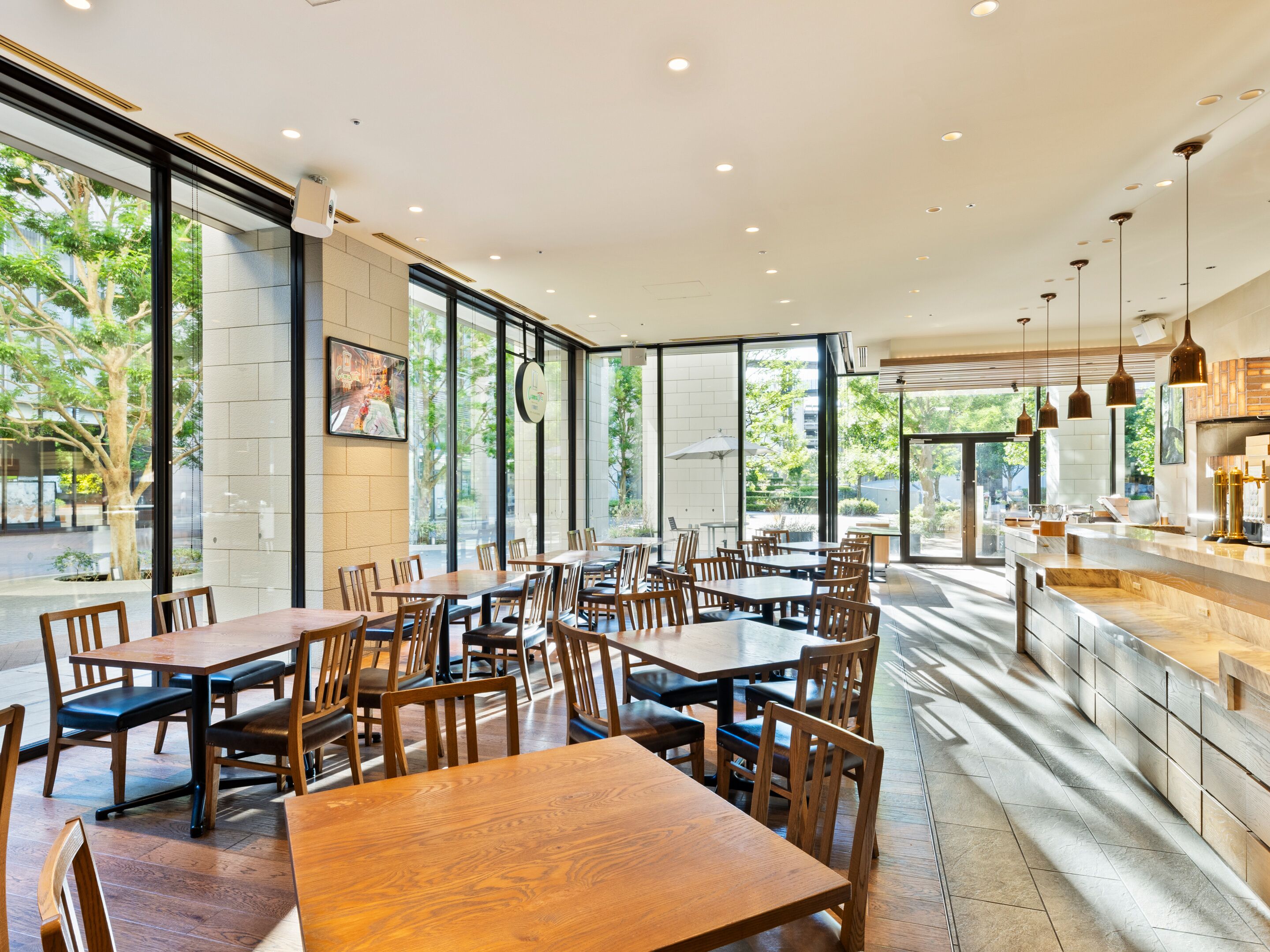 Un restaurante espacioso con amplias ventanas, mesas y sillas de madera, y un diseño de interiores moderno.