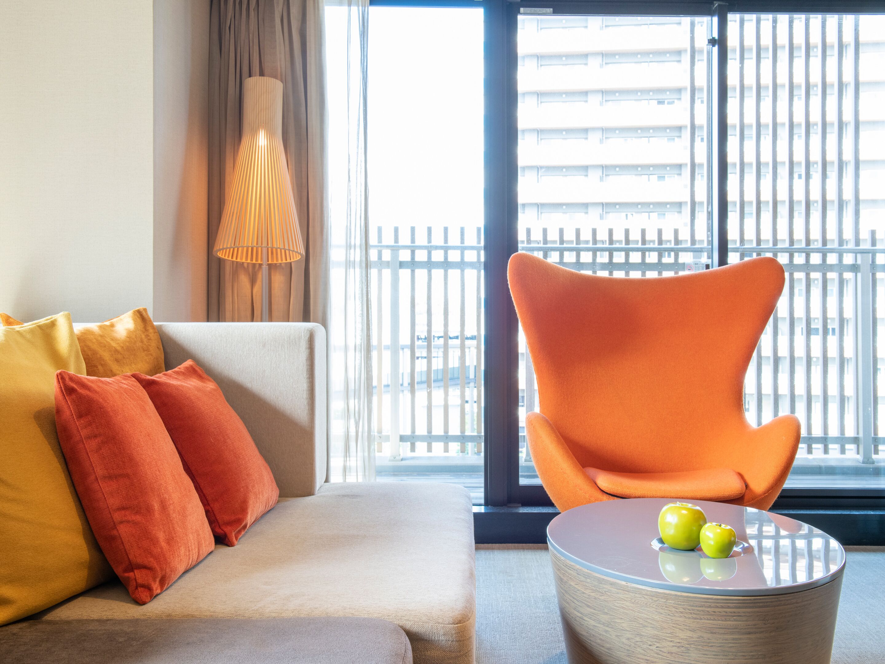 A modern living room with a sofa, orange armchair, and a round coffee table with apples.