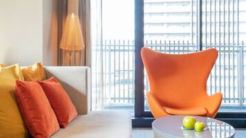 A modern living room with a sofa, orange armchair, and a round coffee table with apples.