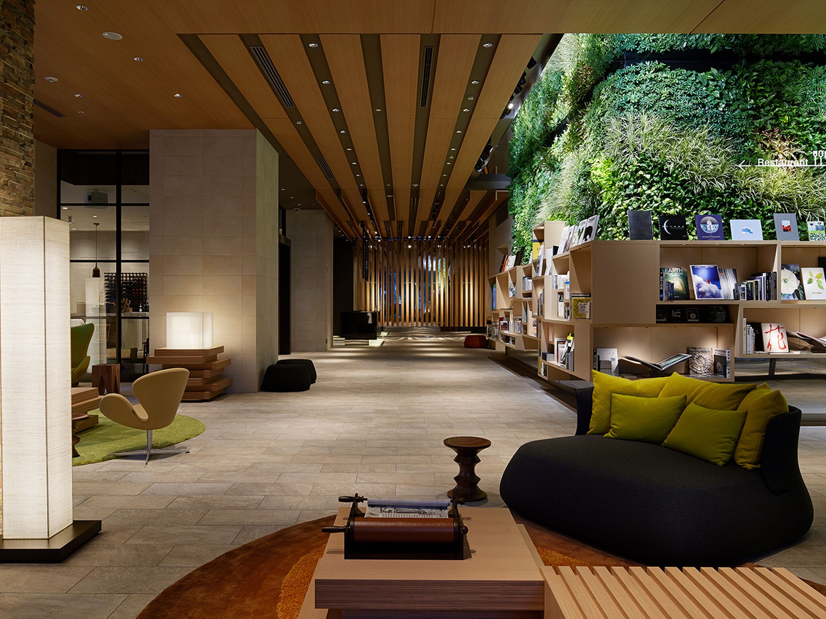 A modern interior with a central seating area, a bookshelf, and a green wall.