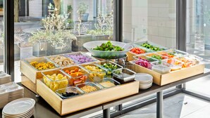 Una mesa de buffet con diversos alimentos y vistas a un edificio y árboles al exterior.