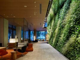 Un interior moderno con un jardín vertical verde, zonas de estar y vistas a través de amplios ventanales.