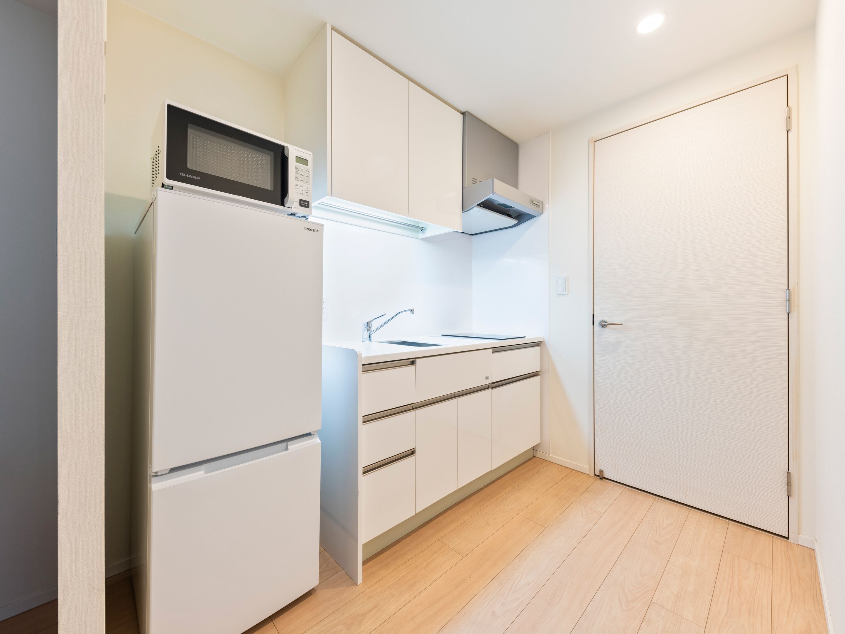 A compact kitchen with a microwave, sink, and cabinets.
