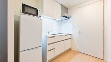 A compact kitchen with a microwave, sink, and cabinets.