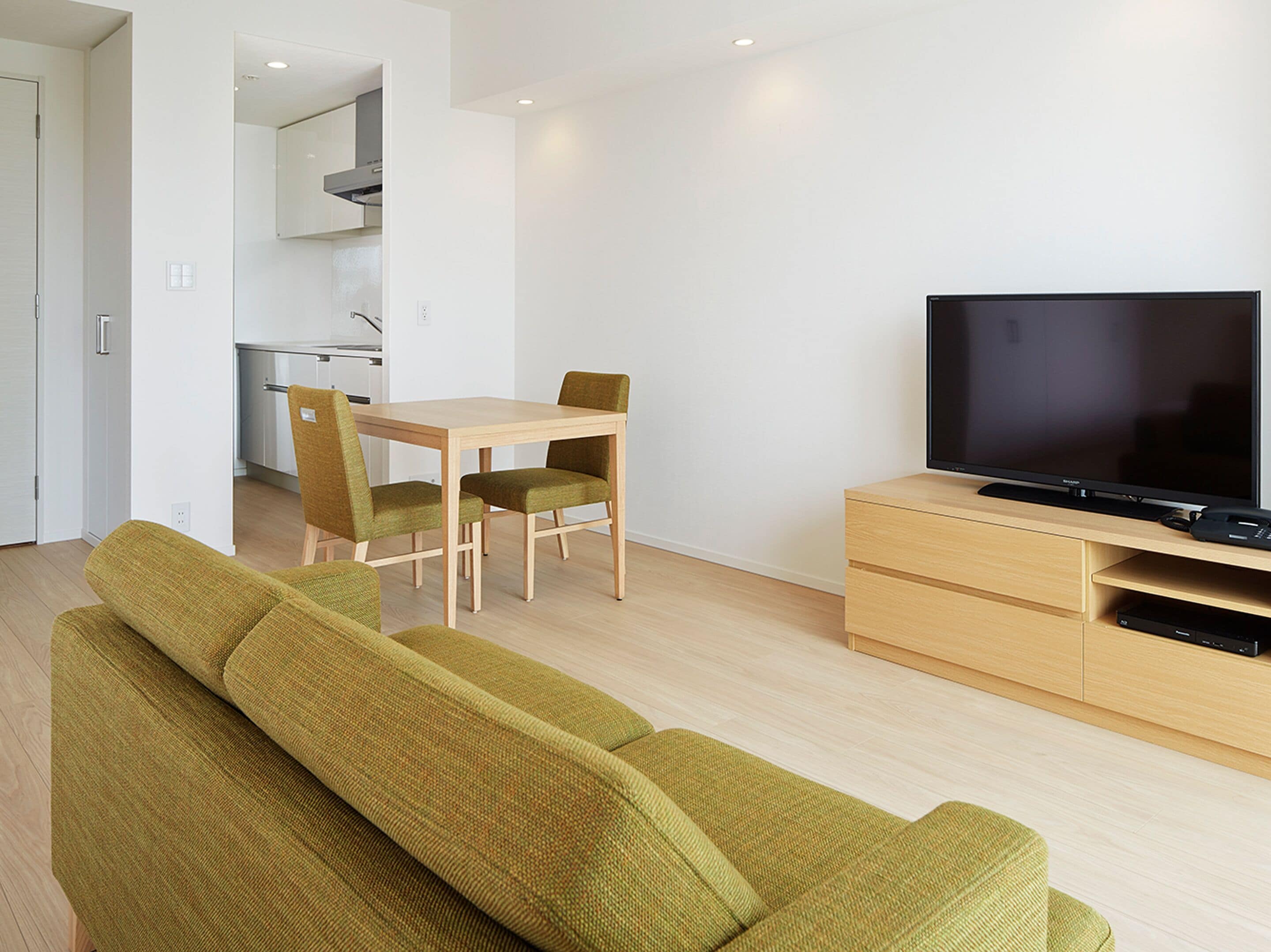 Una sala de estar moderna con un sofá, un televisor y un comedor con sillas y una mesa.