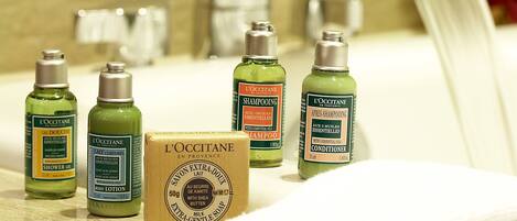 A bathroom counter with various L'OCCITANE products including shampoo, body lotion, and soap.